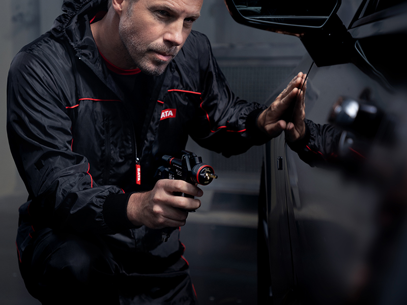 Professional painter inspecting paint finish with SATA jet X HVLP spray gun