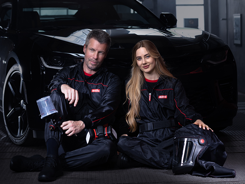 Automotive paint technicians with SATA jet X HVLP spray gun beside freshly painted car